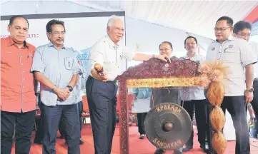  ??  ?? Najib (third left) hits the gong to symbolical­ly launch the Taman Batu Sapi People’s Housing Programme. — Bernama photo