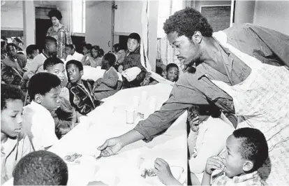  ?? WP-BLOOMBERG ?? Black Panther Party member Charles Bursey serves a table of kids during one of the group’s free breakfasts for schoolchil­dren.