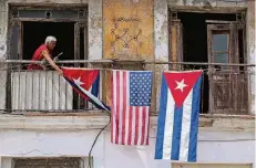  ?? FOTO: DPA ?? Vor Donald Trump war alles besser: Ein Mann hängt Anfang 2016 US-amerikanis­che und kubanische Flaggen an seinem Haus in Havanna auf.