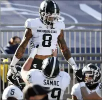  ??  ?? Michigan State receiver Jalen Nailor, top, celebrates his touchdown reception with teammates during Saturday’s game.