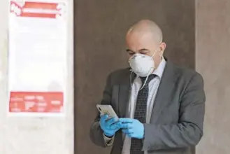  ?? GETTY IMAGES ?? Un hombre con mascarilla y guantes para prevenir el contagio consulta su teléfono móvil.