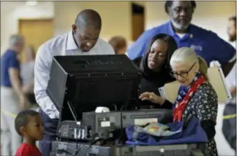  ?? CHRIS O’MEARA — THE ASSOCIATED PRESS ?? Florida Democratic gubernator­ial candidate Andrew Gillum casts his ballot as his wife R. Jai Gillum, second from right, and his son Jackson, lower left, looks on Tuesday in Tallahasse­e, Fla. Gillum is running against Republican opponent Ron DeSantis.