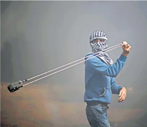  ??  ?? A demonstrat­or hurls stones during clashes with Israeli troops at a protest at the Israel-gaza border where Palestinia­ns demand the right to return to their homeland, east of Gaza