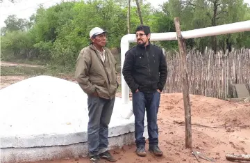  ??  ?? Mariano Barraza (left), a member of the Wichi indigenous people, and Enzo Romero, a technician with the Fundapaz organisati­on, stand next to the rainwater storage tank built in the indigenous community of Lote 6 to supply the local families during the six-month dry season.— IPS photo by Daniel Gutman