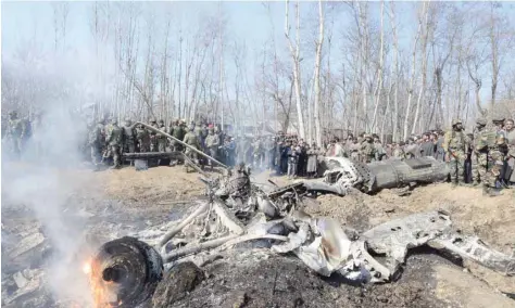  ?? — AFP ?? Soldiers and Kashmiri onlookers stand near the remains of an Indian Air Force fighter jet after it crashed in Budgam district, some 30 kms from Srinagar, on Wednesday.
