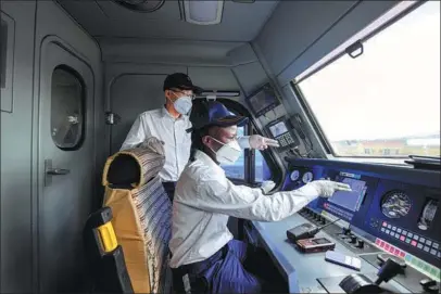  ?? LI YAN / XINHUA ?? A Chinese train driver (left) coaches a local colleague in Nairobi, Kenya, in March.