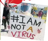  ??  ?? 洛杉矶唐人街一名戴口­罩和透明面罩的华裔女­子，手持“我不是病毒”标语。（法新社照片）