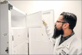  ?? ?? Anthony Martinez, a public health microbiolo­gist, checks a freezer where patients’ COVID-19 specimens are stored at about minus 70Celsius at the newly expanded public health lab.