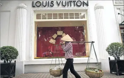  ??  ?? Una mujer vietnamita camina frente a una tienda de lujo en el barrio francés de Hanói