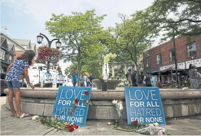  ?? COLE BURSTON/GETTY IMAGES ?? A young girl writes with chalk on a makeshift memorial on Danforth Ave.