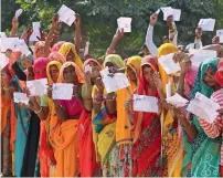  ?? PTI ?? Voters show their identity cards as they queue up to cast their vote, outside a polling station at Samred village of Jaipur district on Friday. On right, Rajasthan Chief Minister Vasundhara Raje at her Jhalrapata­n constituen­cy in Jhalawar. —