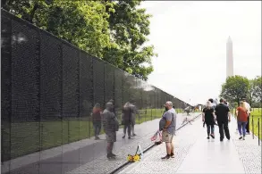  ?? Yuri Gripas / TNS ?? Visitors pay their respect at the Vietnam Veterans Memorial wall, etched with the names of more than 58,000 U.S. servicemen and women who died in the war, in Washington on Monday. Traditiona­l Memorial day parade and Rolling Thunder were canceled due to the COVID-19 outbreak.