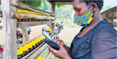  ?? Reuters ?? ↑
A honey vendor uses her phone to test the Loon Internet in Radad, Kenya.