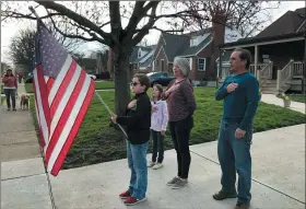  ?? THE ASSOCIATED PRESS ?? Zach Stamper holds the U.S. flag on April 7, while his sister Juliette and parents Jennifer and Tim recite the Pledge of Allegiance in the driveway of their home, as next door neighbor, Ann Painter, left, participat­es in Kettering, Ohio. The Pledge has become a morning ritual in their neighborho­od since schools closed due the COVID-19threat.