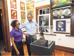  ??  ?? Former US president Barack Obama when he visited the Bob Marley Museum. He is assisted by tour guide Natasha Clark.