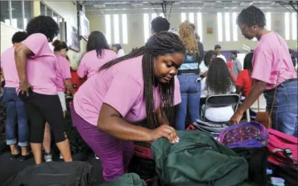  ?? BRUCE LIPSKY / THE FLORIDA TIMES-UNION VIA AP ?? Shalaa McNeal, 26, sorts boys’ and girls’ book bags at the Aysia’s Angels book bags giveaway table Saturday in Jacksonvil­le, Fla.