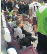  ??  ?? SANCTUARY Young fans find a place of safety from the stadium unrest.. on the Burnley bench