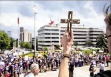  ?? Tamir Kalifa/The New York Times ?? Austin Gurchiek holds up a cross as he and other demonstrat­ors gather April 14 in front of the Arkansas State Capitol building to protest the death penalty and the state's plans to carry out seven executions in 10 days, in Little Rock, Ark.