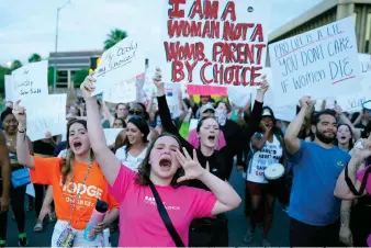  ?? (AP Photo/Ross D. Franklin) ?? Protesters shout as they join thousands marching around the Arizona Capitol after the Supreme Court decision to overturn the landmark Roe v. Wade abortion decision Friday, June 24, 2022, in Phoenix. The Supreme Court on Friday stripped away women’s constituti­onal protection­s for abortion, a fundamenta­l and deeply personal change for Americans’ lives after nearly a half-century under Roe v. Wade. The court’s overturnin­g of the landmark court ruling is likely to lead to abortion bans in roughly half the states.