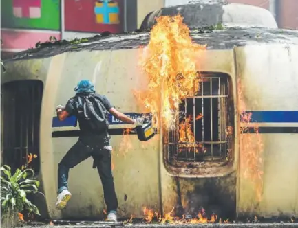  ?? Ronaldo Schemidt, AFP ?? Venezuelan demonstrat­ors set fire to a small police station during an anti-government protest in Caracas. Sporadic violence broke out Thursday during a 24-hour nationwide strike.