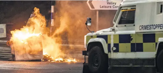  ?? KEVIN SCOTT ?? Battlegrou­nd: Police approach a burning bin in the Cloughfern area of Newtownabb­ey last night