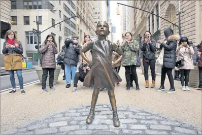  ?? [MARK LENNIHAN/THE ASSOCIATED PRESS] ?? The popularity of this bronze statue of a ponytailed girl in a windblown dress might keep it on Wall Street beyond its scheduled removal on Sunday. It was installed in front of Wall Street’s famous bronze bull earlier this month.