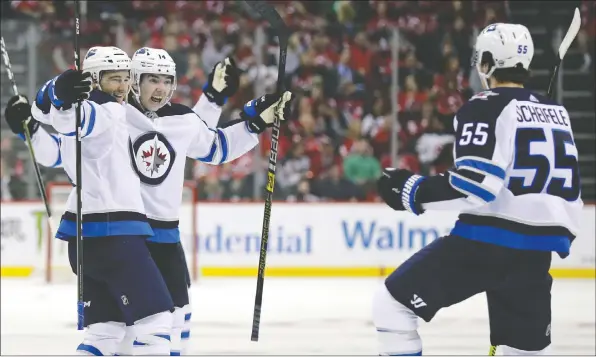  ?? ADAM HUNGER/GETTY IMAGES ?? Jets players celebrate scoring in the third period against the New Jersey Devils on Friday night. Winnipeg rallied for a 5-4 shootout win.