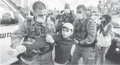  ?? — Gambar AFP ?? TAHAN: Anggota polis Israel menahan seorang aktivis warga Israel semasa demonstras­i di Jerusalem.