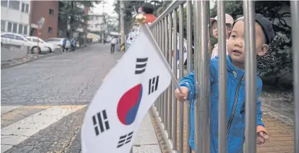  ?? AFP ?? A child waves a flag as supporters of new South Korean President Moon Jae-in wait outside his Seoul home to congratula­te him yesterday.