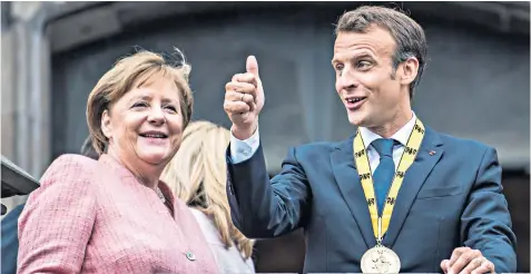  ??  ?? Angela Merkel, the German chancellor, and Emmanuel Macron, the French president, on the balcony of Aachen town hall yesterday after he was awarded the Charlemagn­e Prize