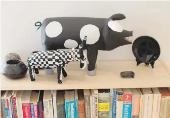  ??  ?? A Navajo black-and-white polka-dot pig carving stands next to a checkerboa­rd zebra beaded in Africa. The small bowl, with a black-on-black glaze, was made by Pueblo potter Maria Montoya Martinez.