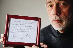  ??  ?? Priceless: Horacio Gaggioli holding a framed copy of the napkin linking a 13-yearold Lionel Messi to Barcelona. — AP