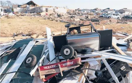  ?? JAMES KENNEY/AP ?? A wagon lies among debris along Moss Creek Avenue, where 11 people died, in Bowling Green, Ky. Three others died in the same subdivisio­n.