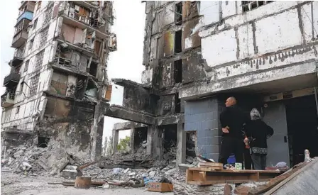  ?? AP ?? Residents stand amid the rubble of destroyed buildings in Mariupol, Ukraine, on Friday. Russian forces have pounded the port city for months, and Ukrainian authoritie­s announced an end to their combat operation on Monday. Fighters had been holding out in a steel mill.