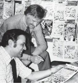 ?? AP ?? Lee, standing, discusses a comic book cover with artist John Romita at Marvel headquarte­rs in New York in this Jan. 10, 1976, file photo.