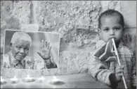  ?? AHMAD GHARABLI / AGENCE FRANCE-PRESSE ?? Candles light a photo of late South African president Nelson Mandela during a vigil by Palestinia­ns and members of the African community in the Old City of Jerusalem on Saturday. Mandela died on Thursday at the age of 95.