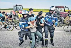  ??  ?? Confrontat­ion: police detain a protester as Geraint Thomas, third left, rides by