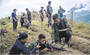  ?? FEDERICO RIOS ESCOBAR FOR THE NEW YORK TIMES ?? Two members of the old FARC teaching a new FARC member how to use his assault rifle at a shooting camp.