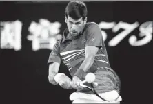  ?? LUCY NICHOLSON / REUTERS ?? Serbia's Novak Djokovic hits a return to France's Jo-Wilfried Tsonga during their Australian Open second-round clash at Melbourne Park on Thursday. The match, which ended in the wee hours of Friday, saw top seed Djokovic win 6-3, 7-5, 6-4 in a rematch of the 2008 final.