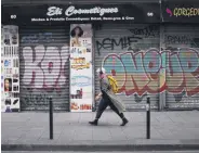  ??  ?? A woman walks past a closed hair and cosmetics shop in Paris, France, Nov. 19, 2020.