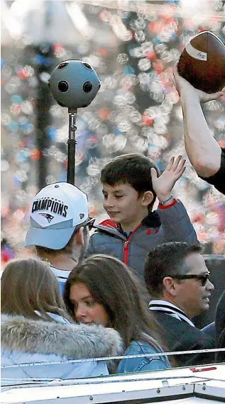  ?? AP ?? New England Patriots quarterbac­k Tom Brady tosses a football as the team parades through downtown Boston yesterday.