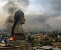  ?? The Associated Press ?? ■ Smoke billows from the base of a sculpture depicting Iraqi President Saddam Hussein after looters set it on fire atop the roof of his Al-Salam Presidenti­al Palace on April 13, 2003, in Baghdad.