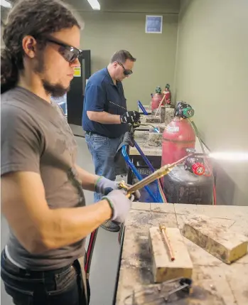  ?? RIC ERNST/PNG ?? Students Jesse Kouwenhove­n, left, and Tony Sabo braze copper pipe at the Joint Apprentice Refrigerat­ion Training School in Surrey on Thursday. Getting on-the-job training is a major hurdle in the trades industry.