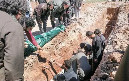  ?? Fadi Al-Halabi/AFP/Getty Images ?? Syrians dig a grave Wednesday to bury the bodies of victims of a suspected toxic gas attack in Khan Sheikhun, a rebel-held town in Syria’s northweste­rn Idlib province.