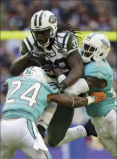  ?? THE ASSOCIATED PRESS ?? The Jets’ Chris Ivory, center, is tackled by Miami Dolphins’ Brice McCain, left, and Reshad Jones on Sunday. Ivory ran for a career-high 166yards in the team’s 27-14win against the Miami Dolphins.