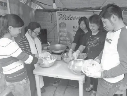  ?? Photo by Bong Cayabyab ?? MUSHROOM TEMPURA. Department of Agricultur­e- CAR research specialist Nestor Humiyat (extreme right) shows how to prepare and cook mushroom tempura during the Agri- Tourism Fair graced by Mayor Mauricio Domogan at the Igorot Park.