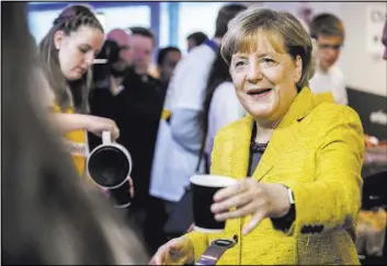  ?? Michael Kappeler The Associated Press ?? Chancellor Angela Merkel drinks a cup of coffee Saturday with election campaign workers in Berlin.