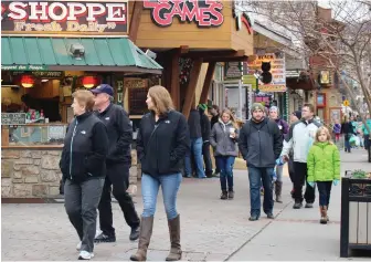  ??  ?? NOW AND THEN: Strollers survey the attraction­s along Gatlinburg’s Parkway, above, just weeks after fires shut the city down. Although most stores have reopened, there was much devastatio­n, such as the scene below on U.S. Highway 321.