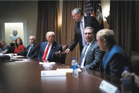  ?? Doug Mills-Pool / Getty Images ?? White House Chief of Staff Mark Meadows hands President Trump a note during a meeting with U.S. Tech Workers. Trump signed an executive order that bans federal agencies from firing U.S. citizens and hiring foreign workers to do their jobs.