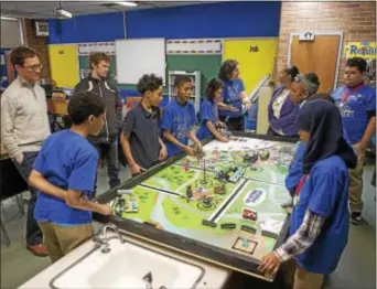 ?? RICK KAUFFMAN — DIGITAL FIRST MEDIA ?? Toby Farms students gather around the standardiz­ed mat in which their robot, automated to complete multiple tasks within a tight time frame, will compete in February.